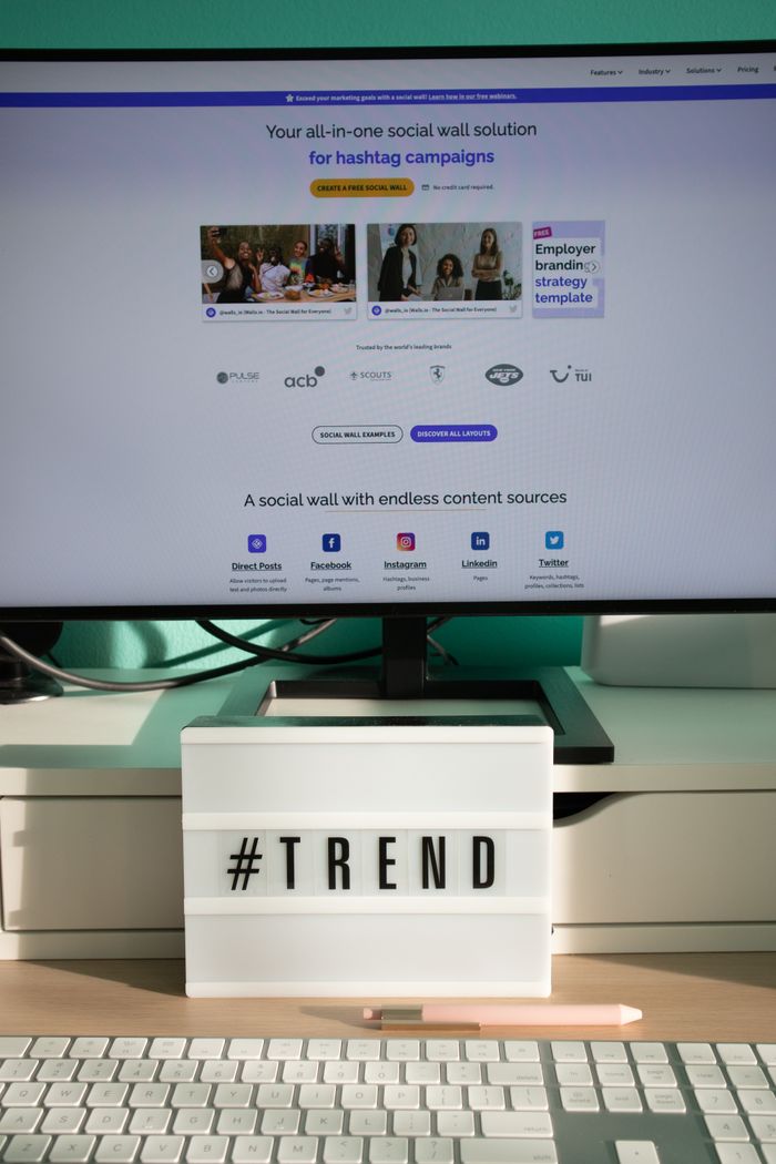 about-us-01 A sleek, contemporary desk arrangement featuring a lightbox that says #TREND and a computer display presenting a social wall solution.